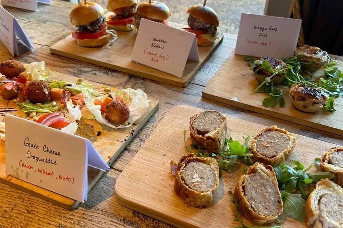 Sharing boards laid out for an event: sausage rolls and goats cheese croquettes with handwritten labels