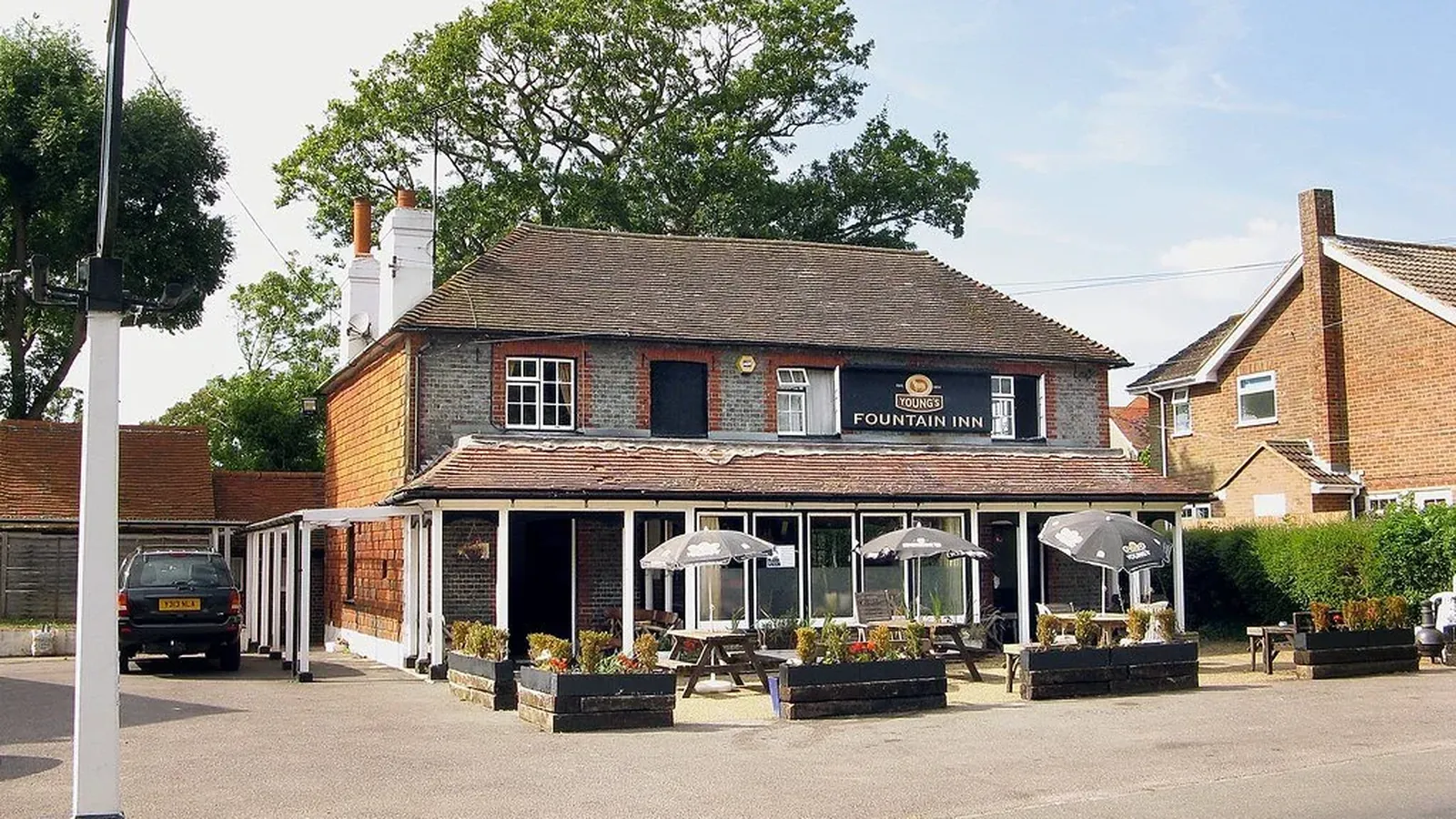 The Fountain Inn seen from Station Road, with parasols and planters along the front terrace